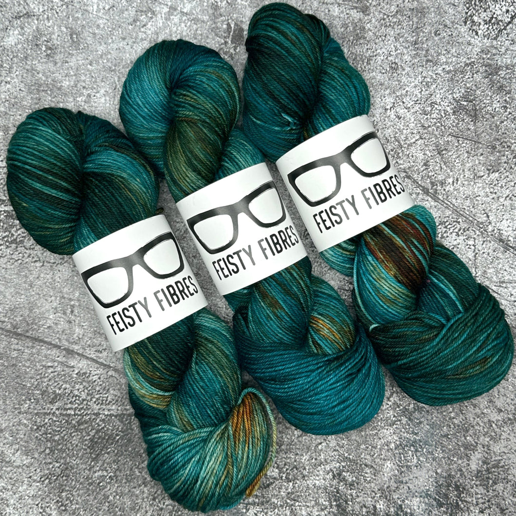 Three skeins of teal yarn with Feisty Fibres labels on a textured gray background