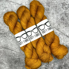 Load image into Gallery viewer, Three skeins of mustard yellow yarn with &#39;Tasty Fibres&#39; labels on a gray textured background
